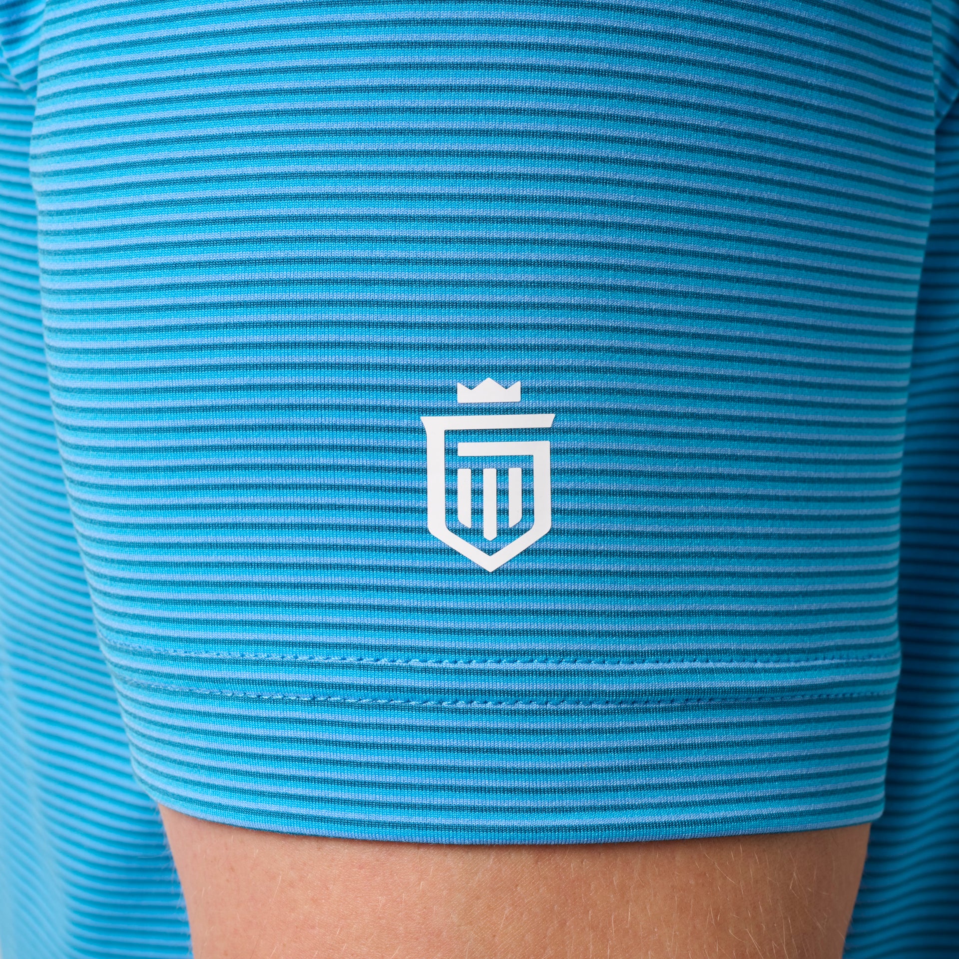Turquoise striped polo shirt with white shield logo on chest.