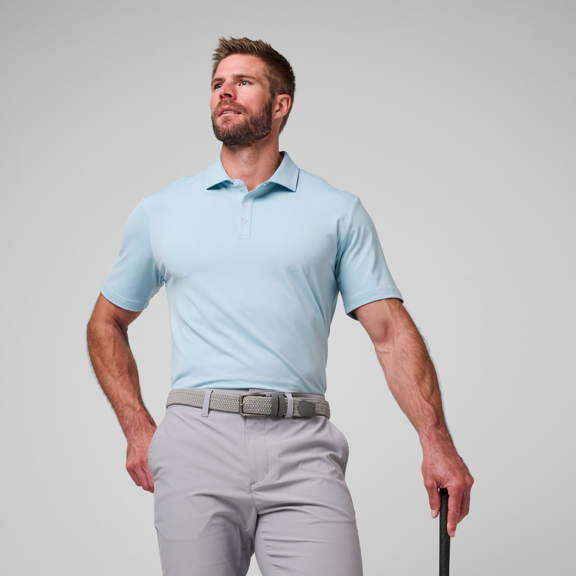 Man wearing light blue short-sleeve polo shirt with collar and gray pants with belt.