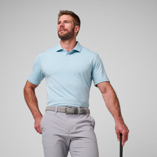 Man wearing light blue short-sleeve polo shirt with collar and gray pants with belt.