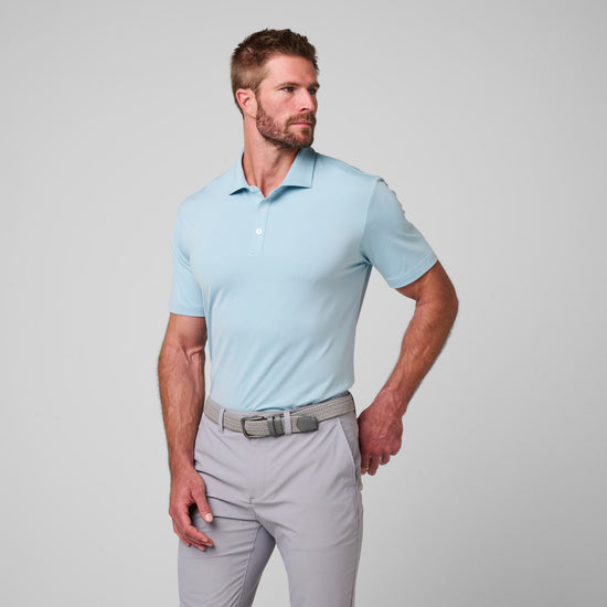 Man wearing light blue short-sleeve polo shirt with collar and white button placket, paired with light gray pants and beige b