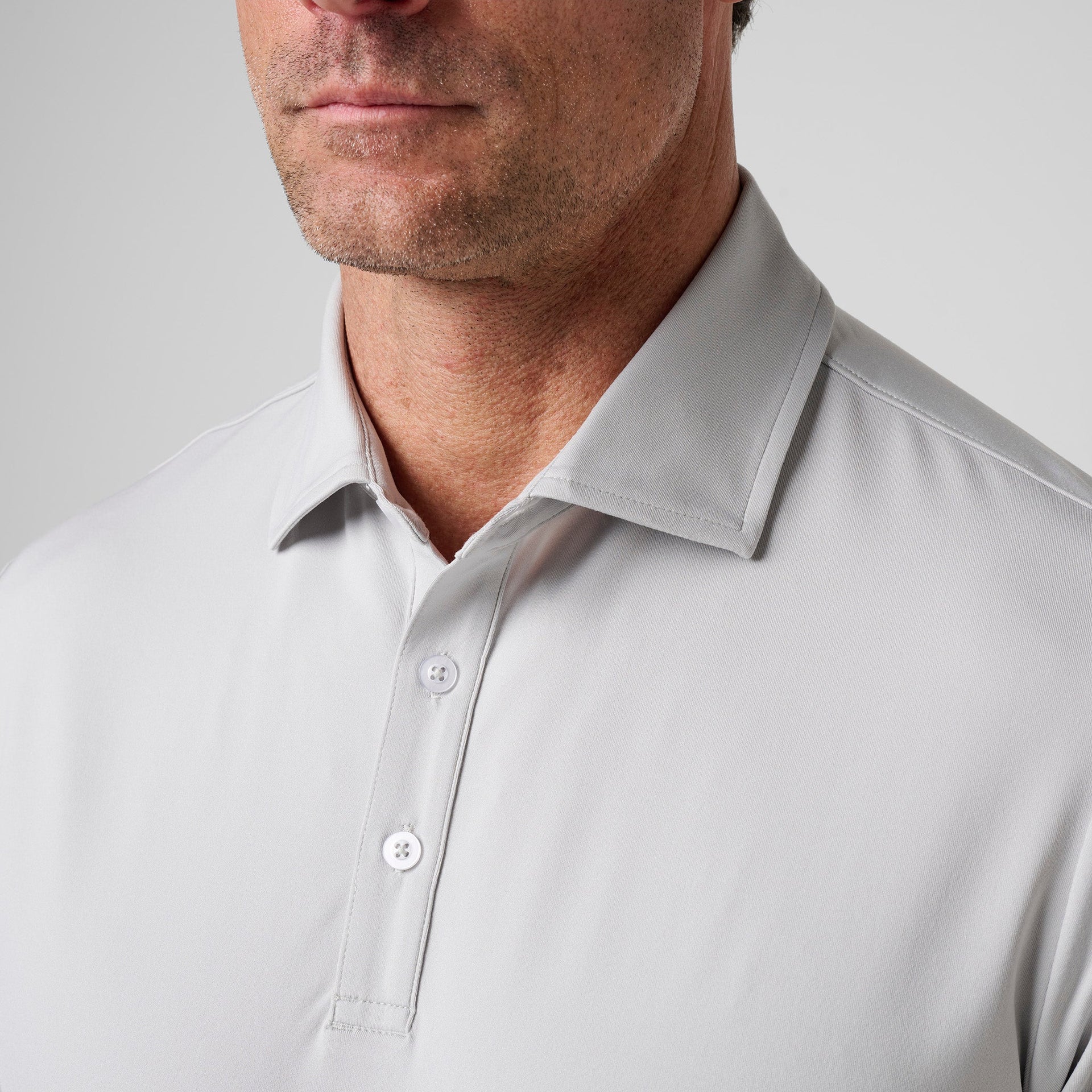 Man wearing light gray polo shirt with collar and white button placket.