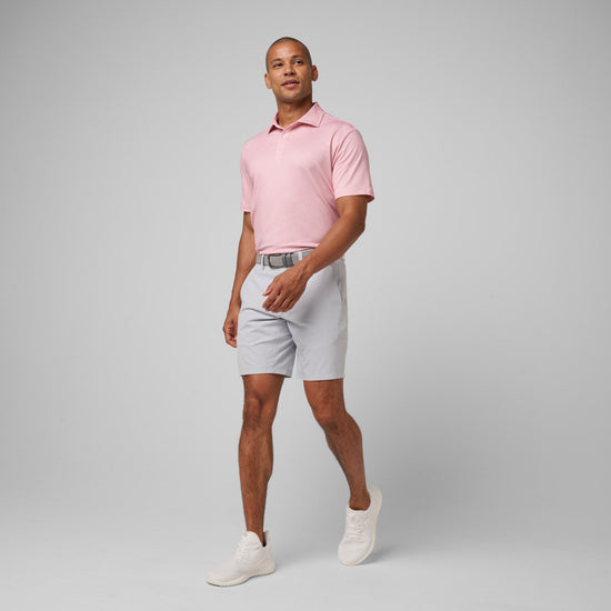 Man wearing pink short-sleeve polo shirt with white shorts and white sneakers.