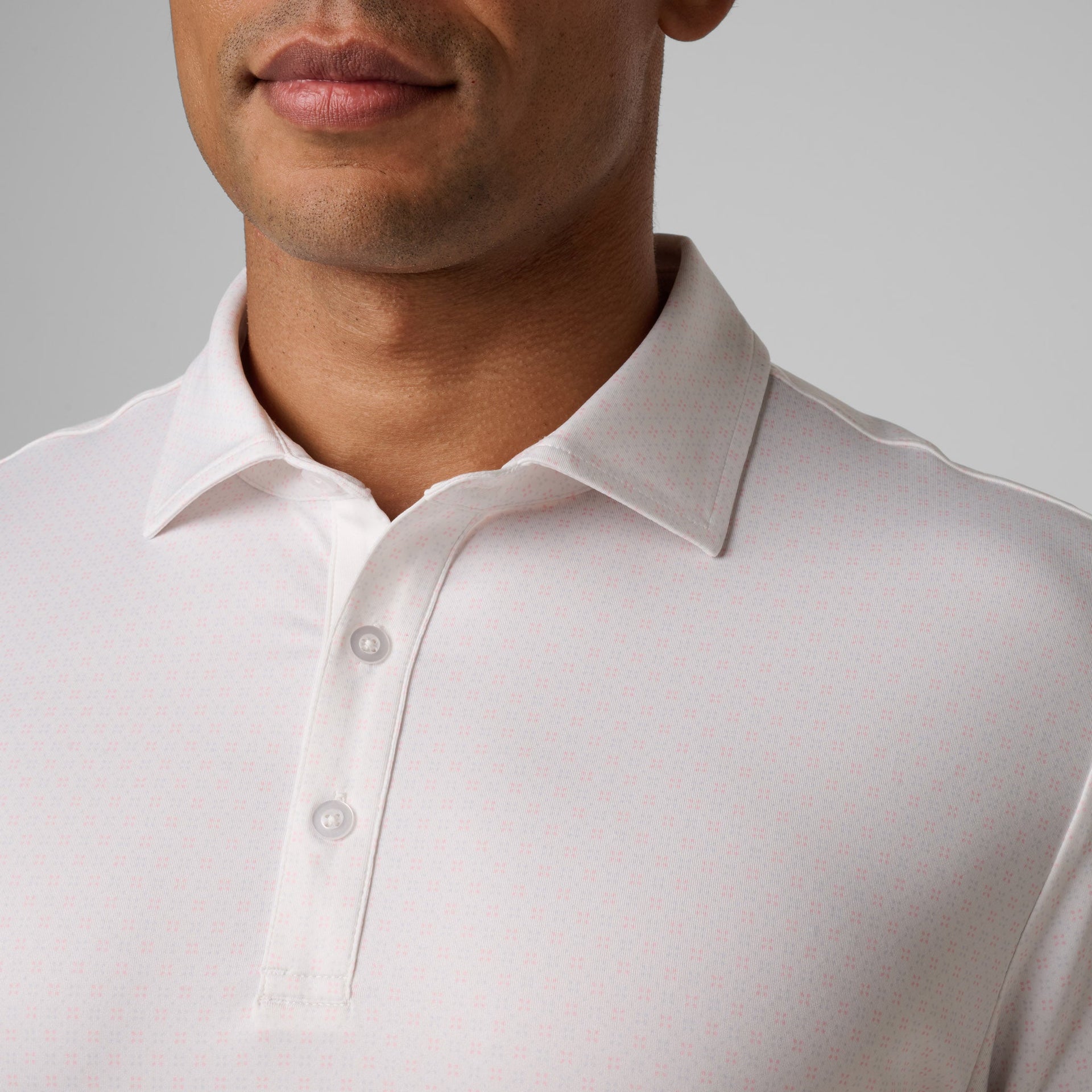 Man wearing white polo shirt with button placket and pointed collar.