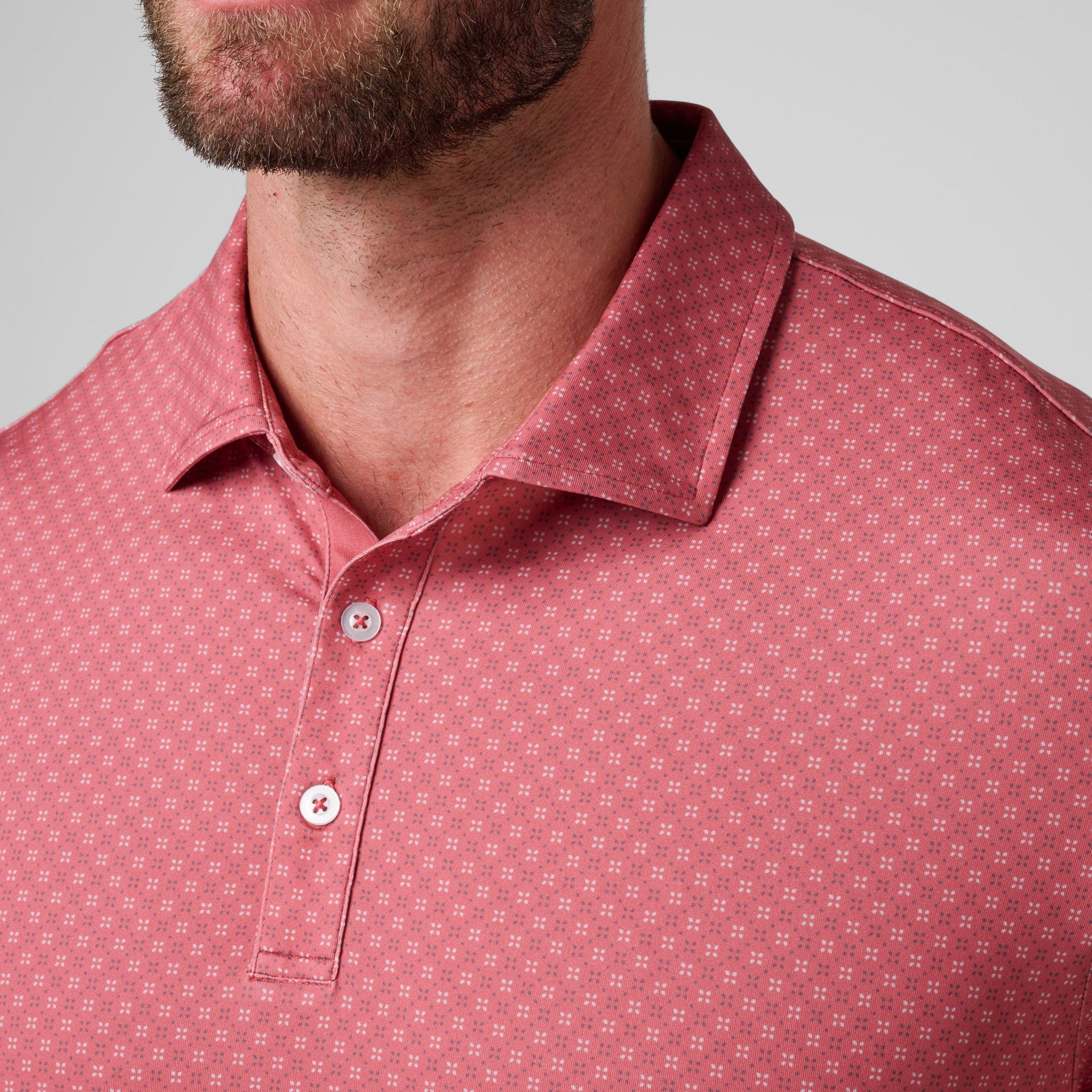 Burgundy polo shirt with all-over small geometric print pattern and white button placket.