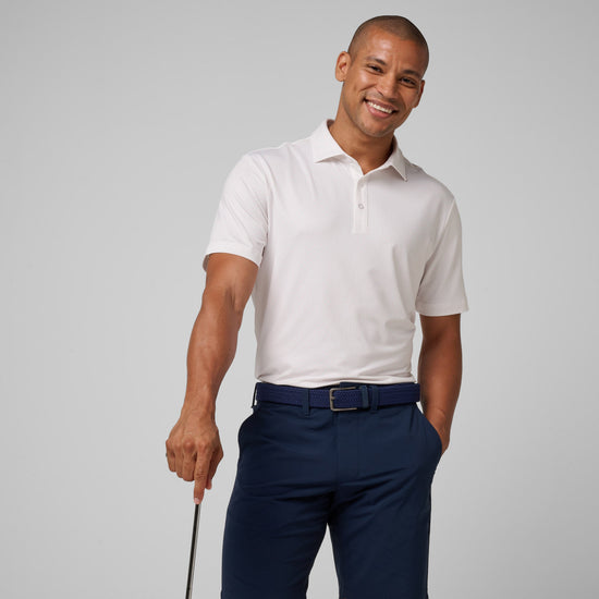 Man wearing white short-sleeve polo shirt with collar and button front, paired with navy pants and blue belt.