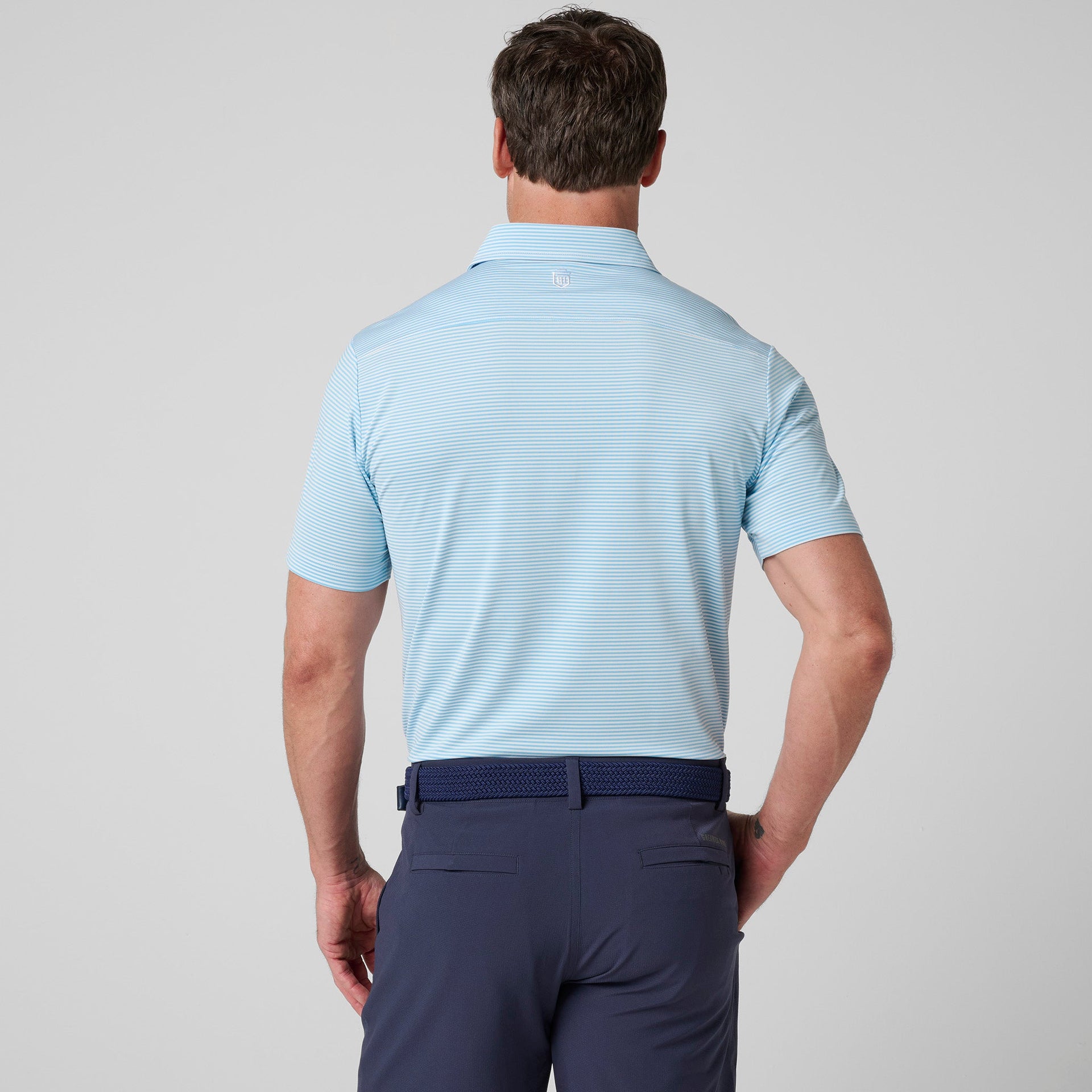 Men's light blue striped polo shirt with short sleeves and collar, paired with dark navy pants, shown from back view.