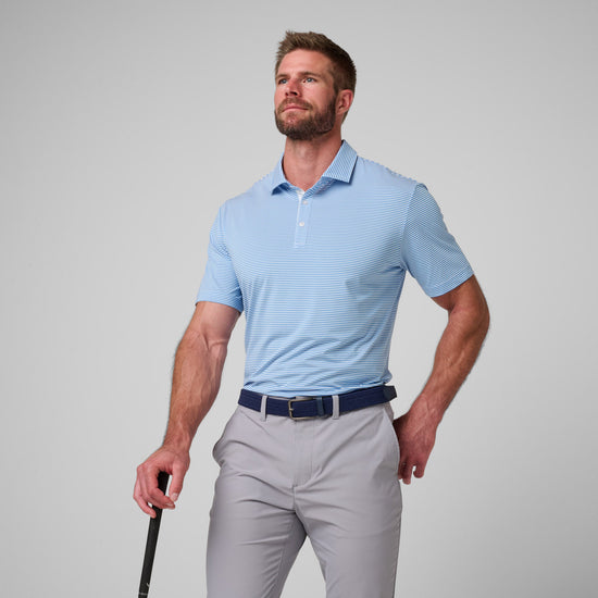 Man wearing light blue striped polo shirt with white buttons and gray pants with navy belt.