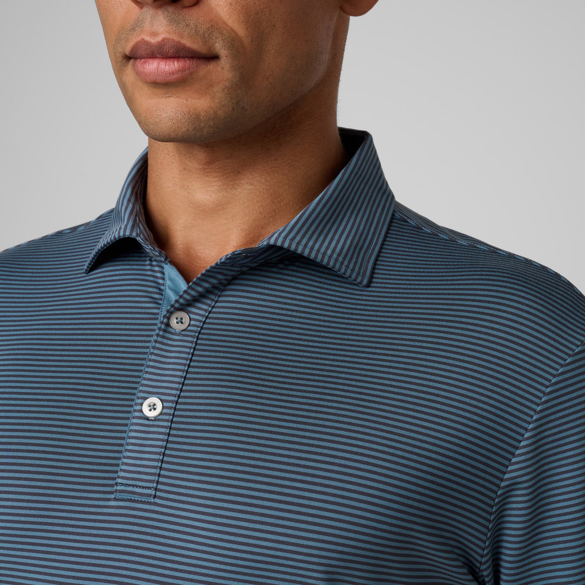 Man wearing blue and navy horizontal striped polo shirt with collar and button placket.