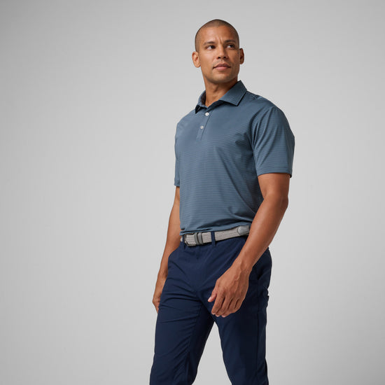 Man wearing blue striped polo shirt with collar and white buttons, paired with navy pants and a gray belt.