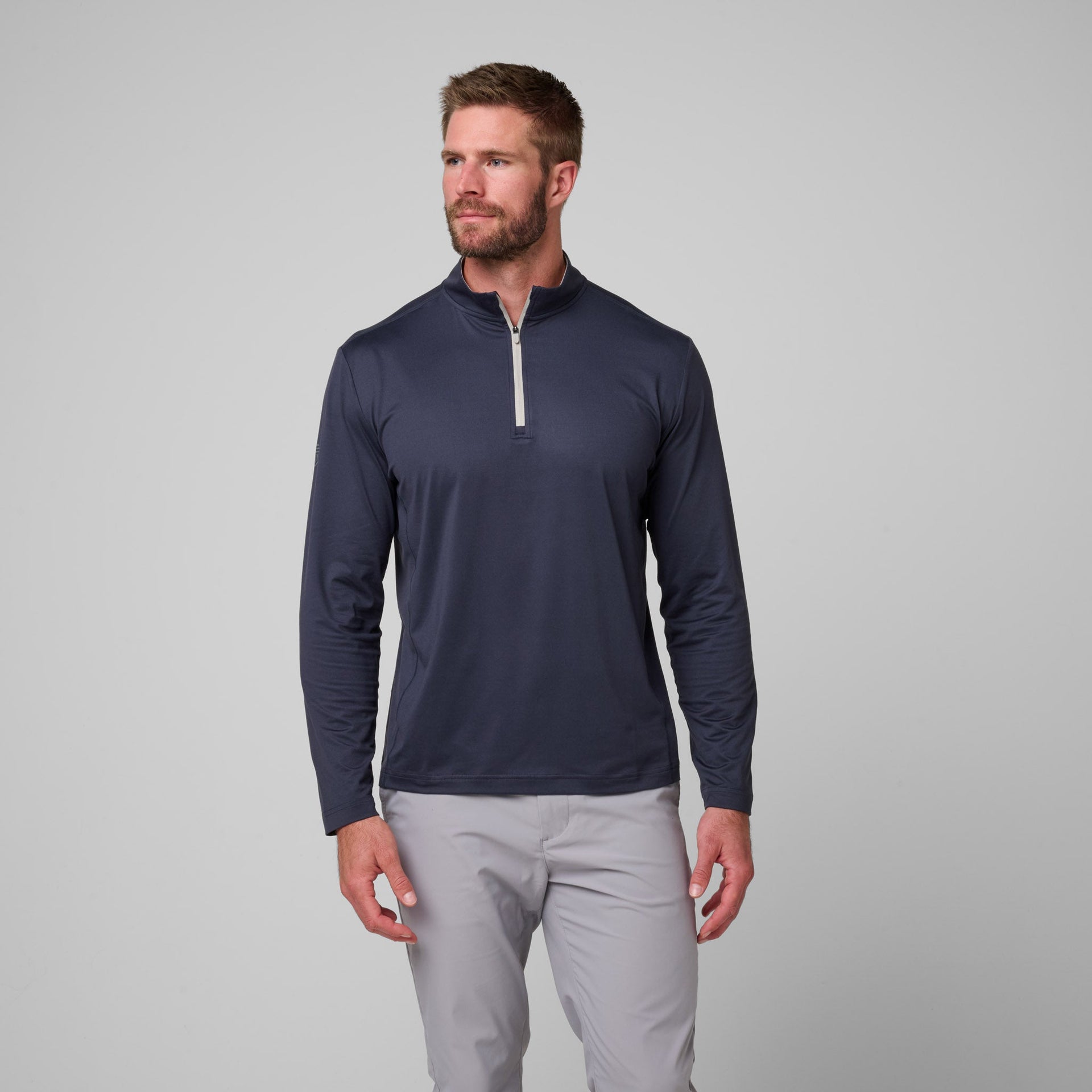 Man wearing navy quarter-zip pullover with white trim and light gray pants.
