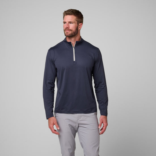 Man wearing navy quarter-zip pullover with white trim and light gray pants.
