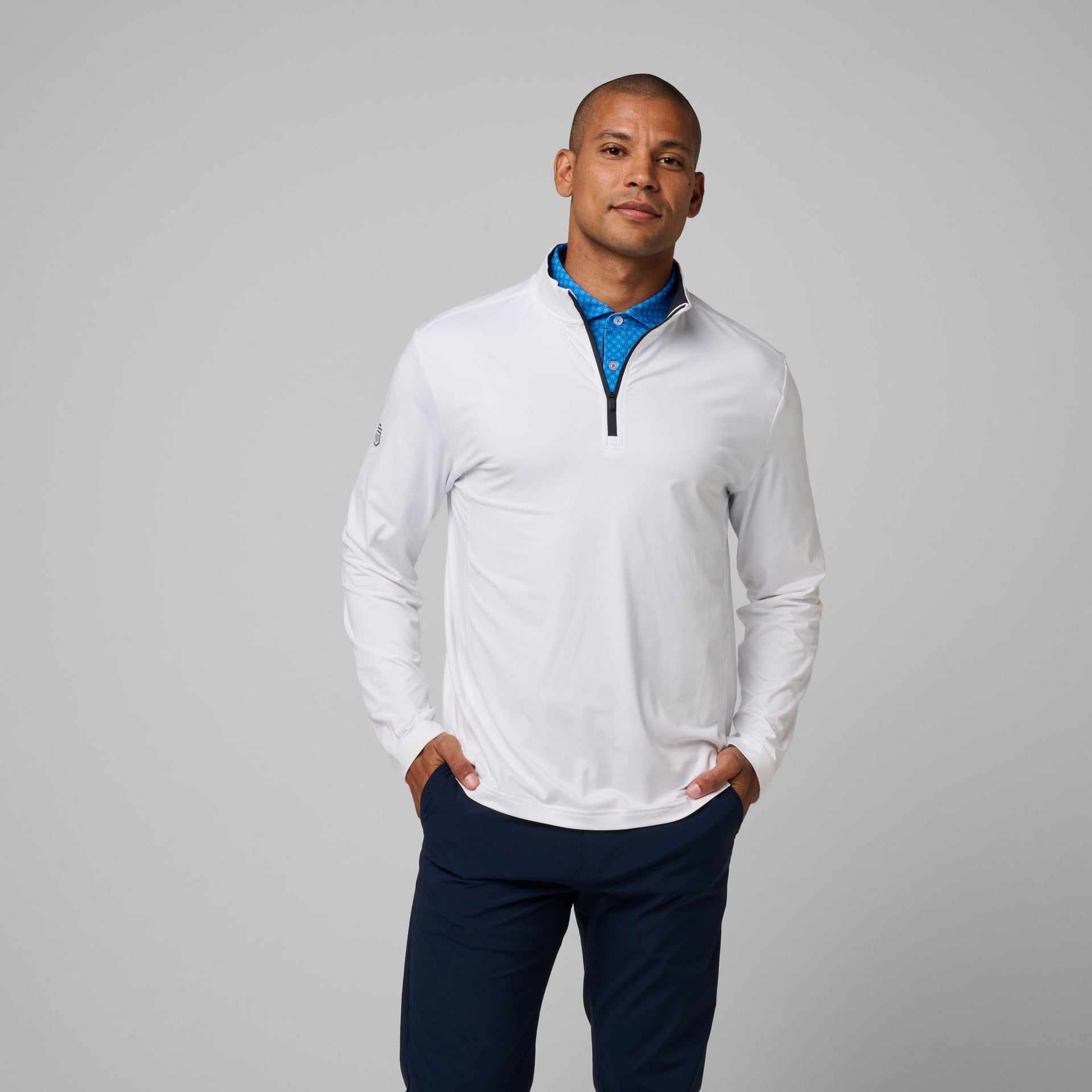 Man wearing white quarter-zip pullover with blue undercollar and navy pants.