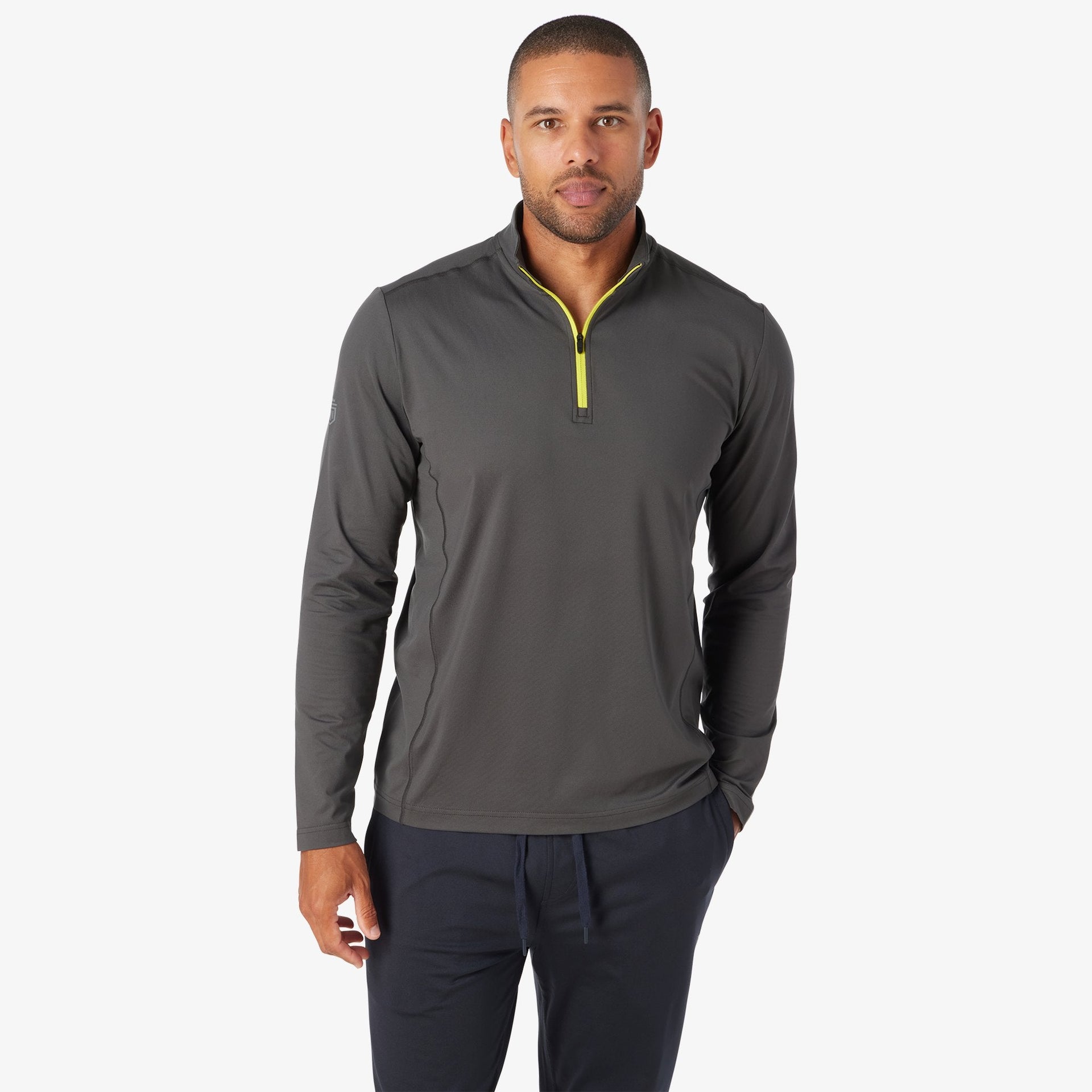 Man wearing charcoal quarter-zip pullover with neon yellow zipper and navy pants.