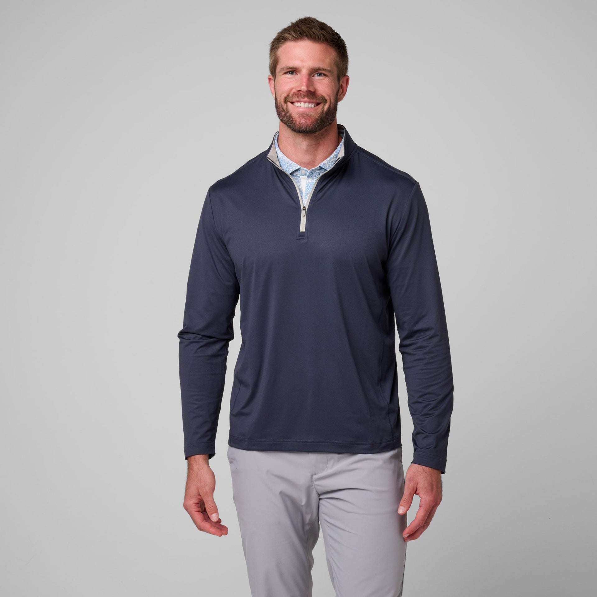 Man wearing navy quarter-zip pullover with light blue collared shirt underneath and gray pants.