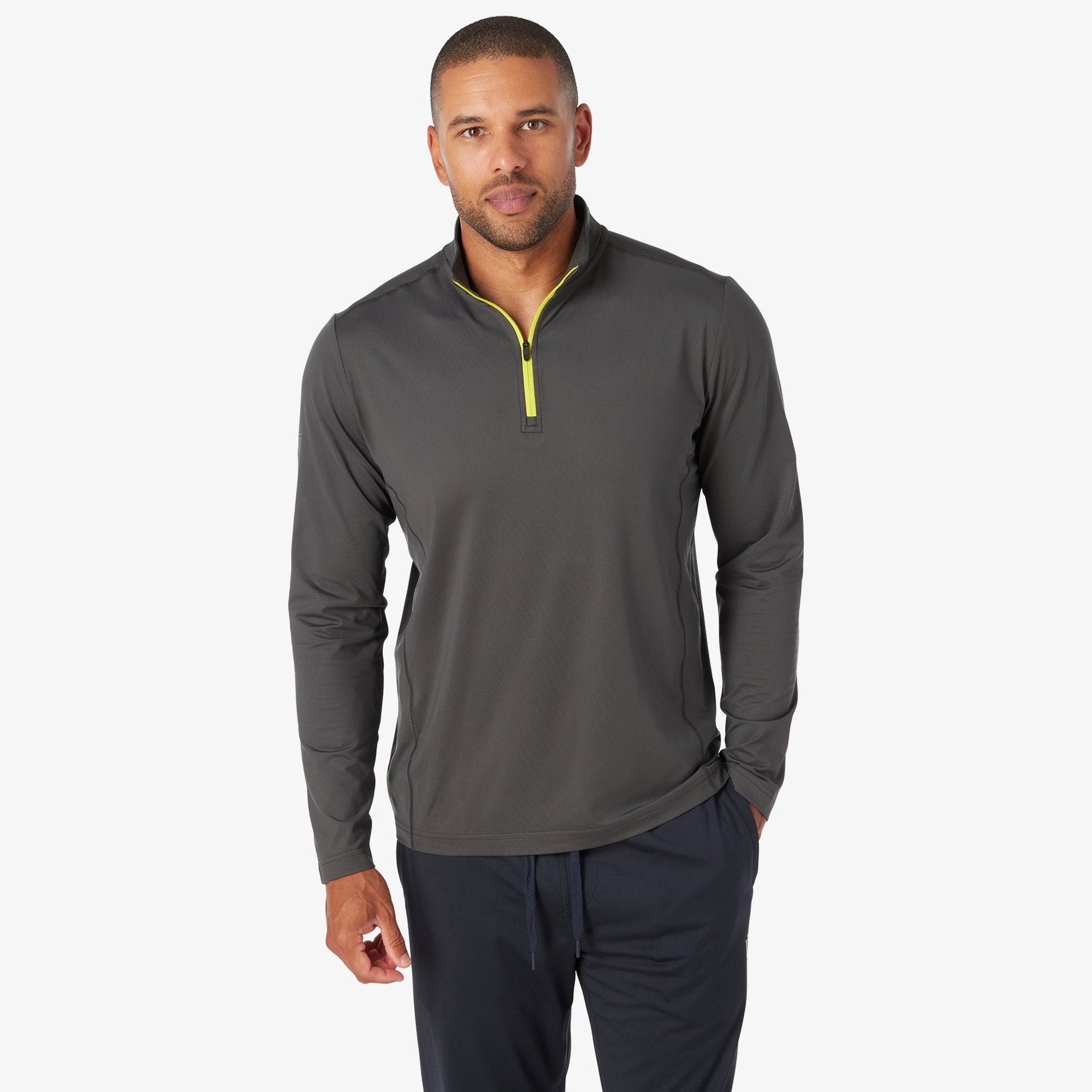 Men's charcoal quarter-zip pullover with yellow zipper detail and navy pants.