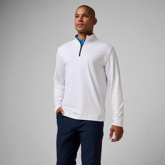 Man wearing white quarter-zip pullover with navy trim and dark navy pants.