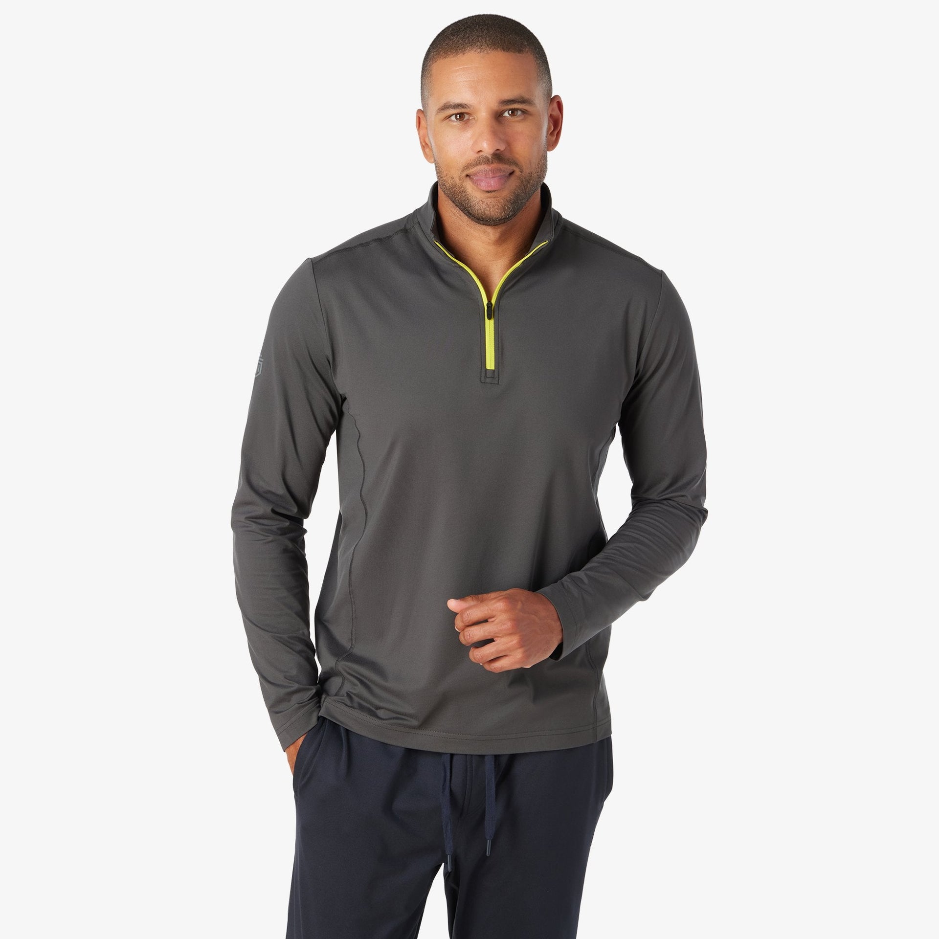 Charcoal quarter zip pullover with yellow zipper and long sleeves worn by man with navy pants.