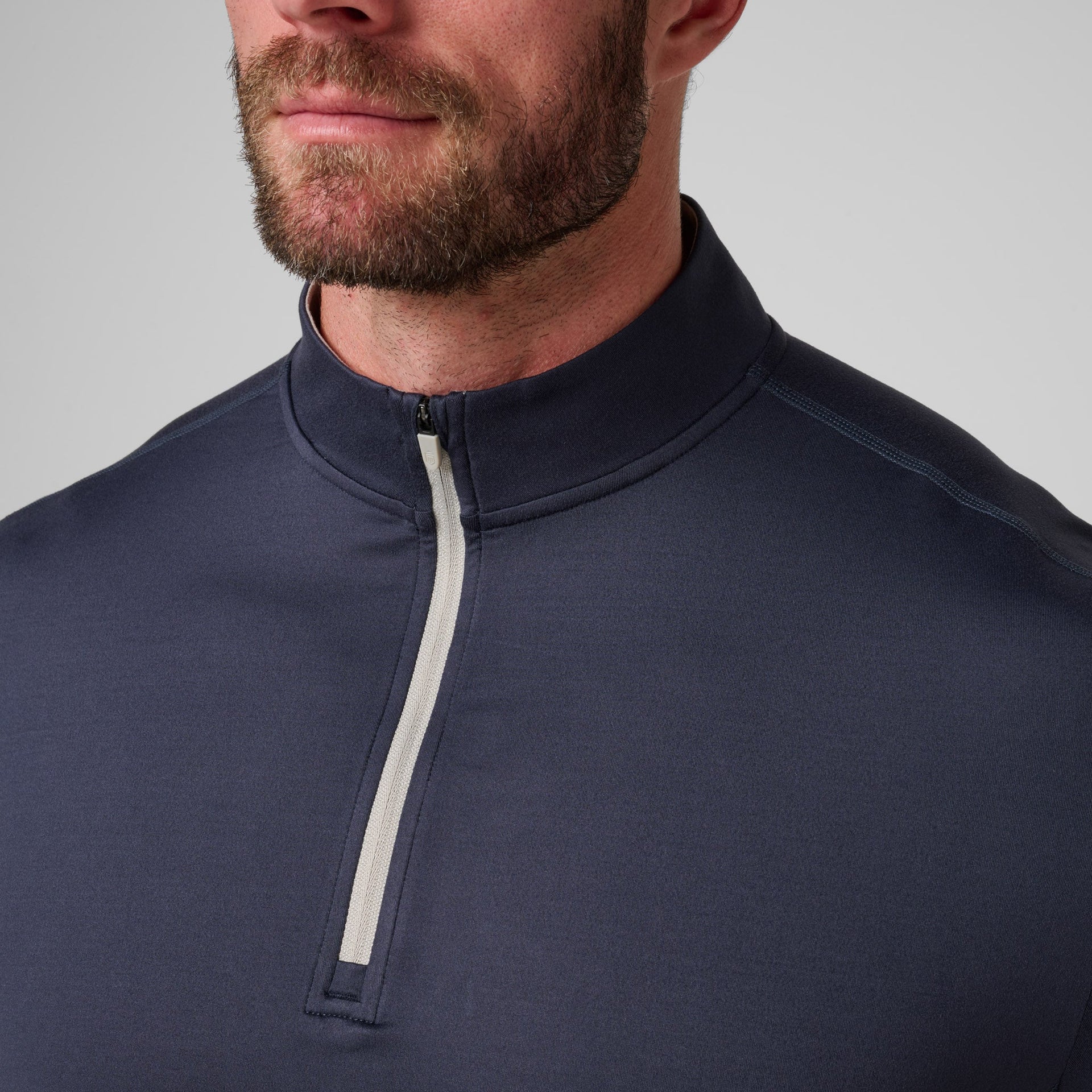 Man wearing navy quarter-zip pullover with white stripe detail on front.