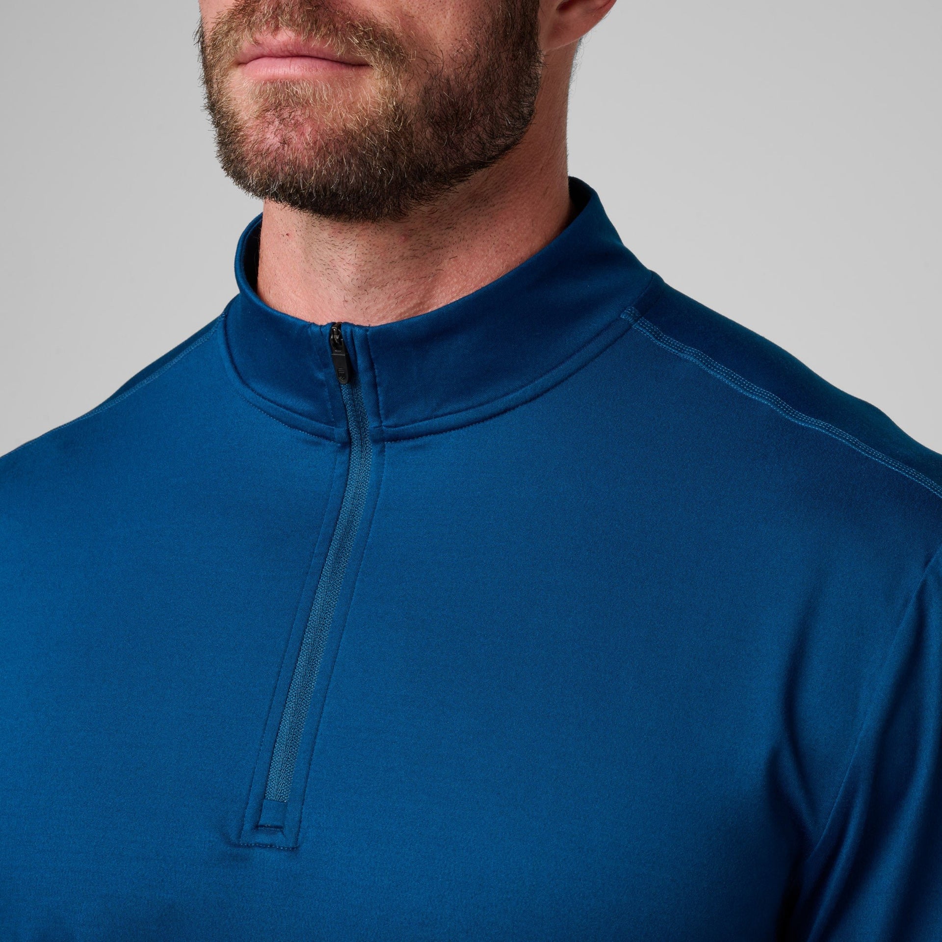 Man wearing a dark blue quarter-zip pullover with a high neckline and visible zipper detail on the chest.