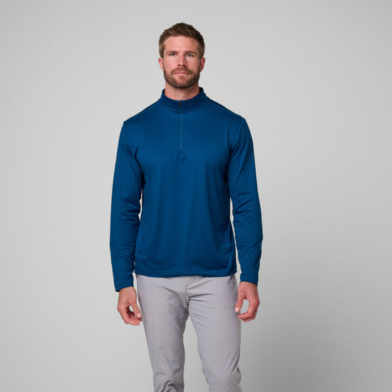 Man wearing navy blue quarter zip pullover with long sleeves and gray pants.