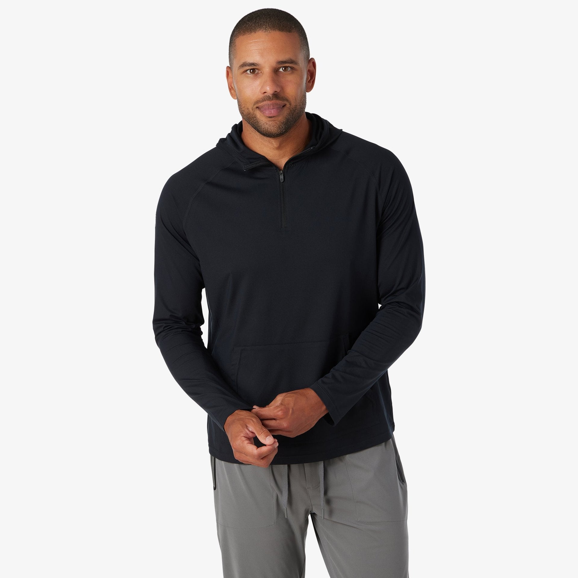 Black quarter-zip hoodie with long sleeves worn with gray pants.