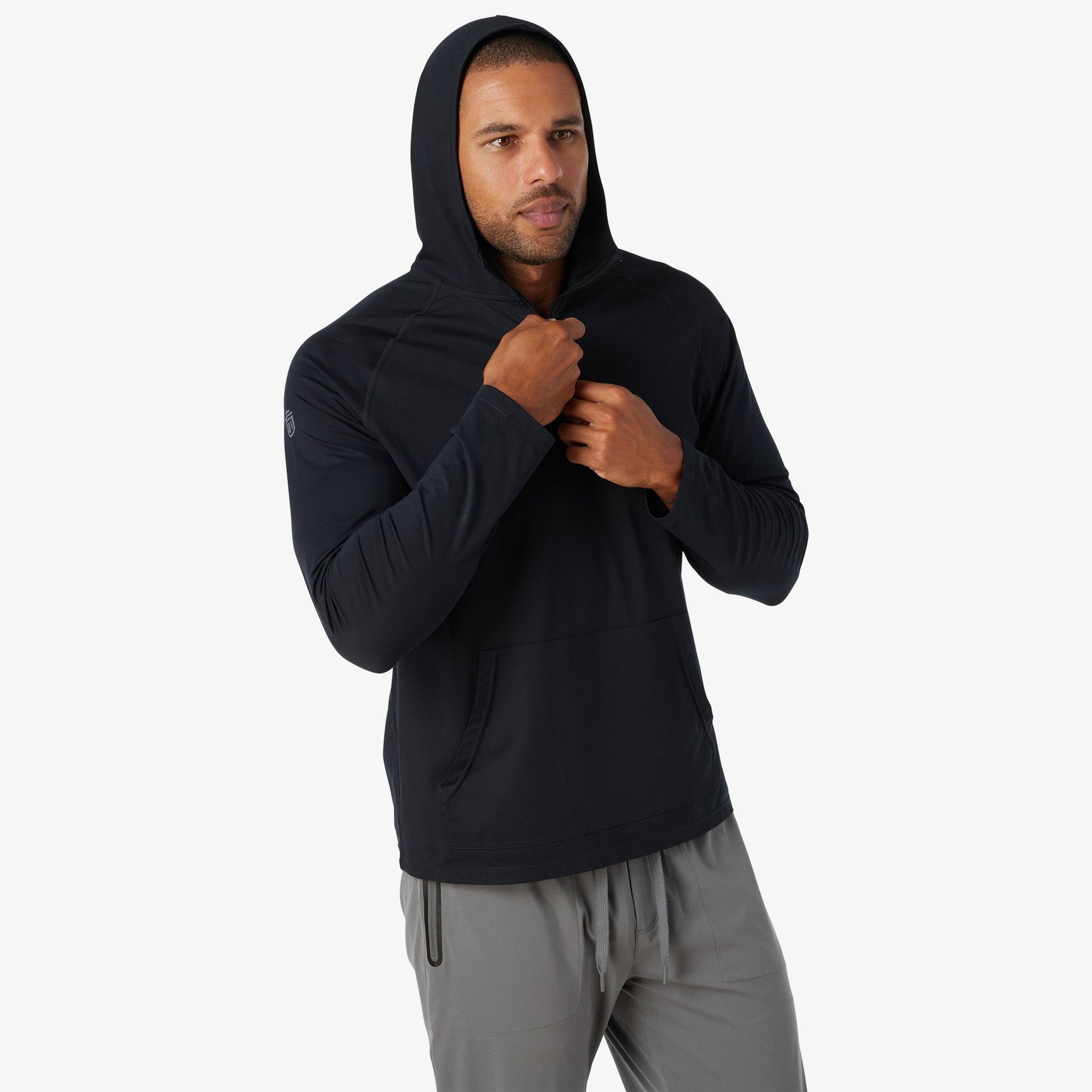 Black quarter zip hoodie with ribbed sleeves worn over gray pants.