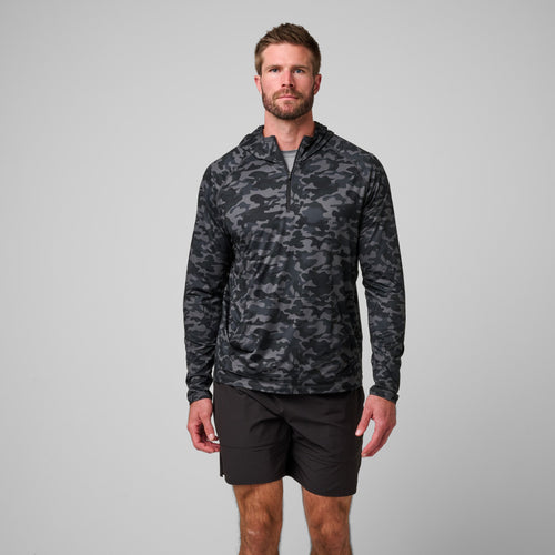 Man wearing charcoal camo quarter zip hoodie with black shorts.