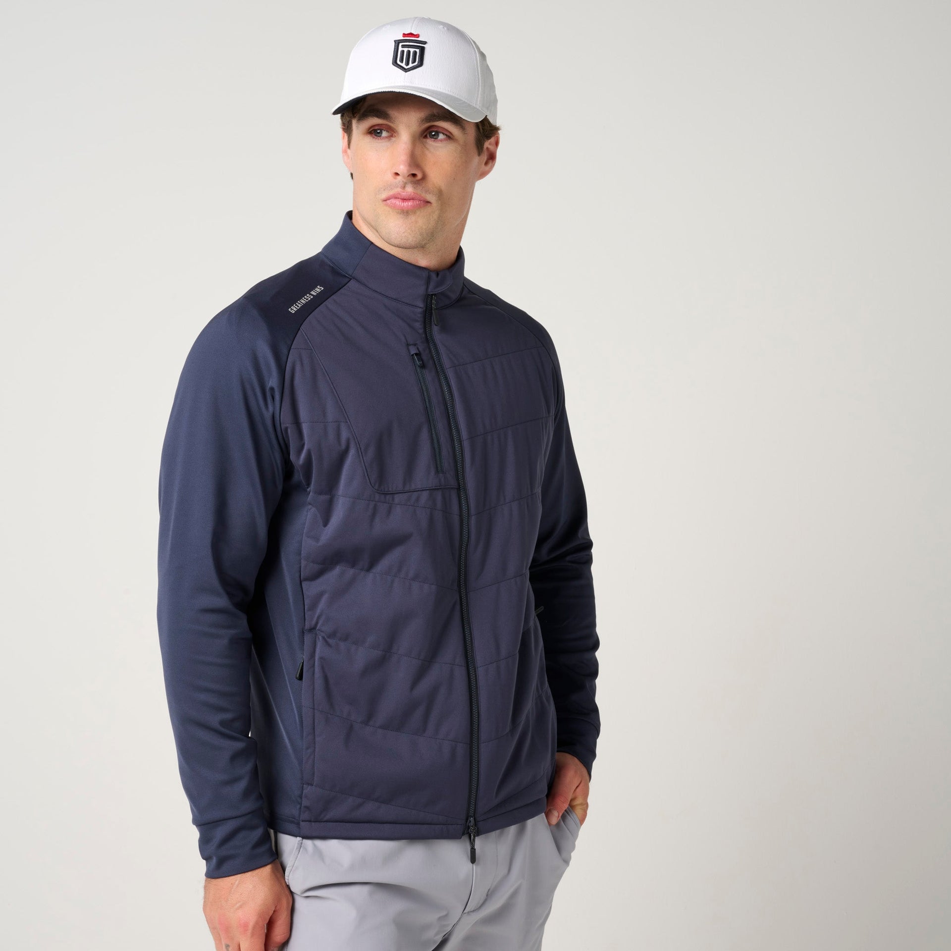 Man wearing navy quilted hybrid jacket with black knit sleeves and full zip front.