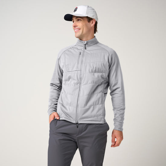 Man wearing light gray quilted hybrid jacket with long sleeves and full-length zipper, paired with charcoal pants.