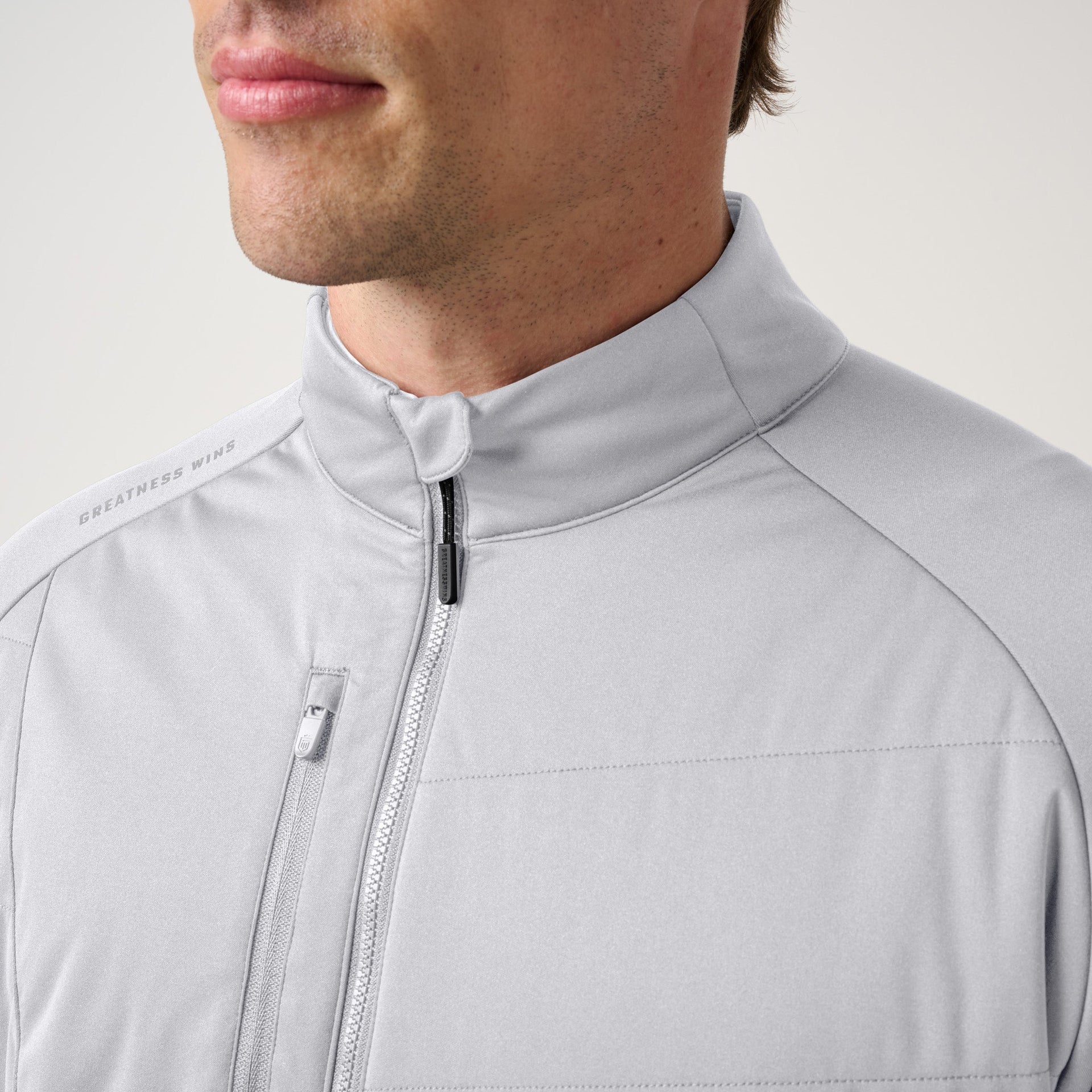 Man wearing light gray hybrid jacket with full-length zipper and chest pocket.