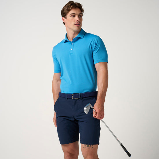 Man wearing bright blue short-sleeve polo shirt with horizontal texture and navy shorts, holding a golf club.