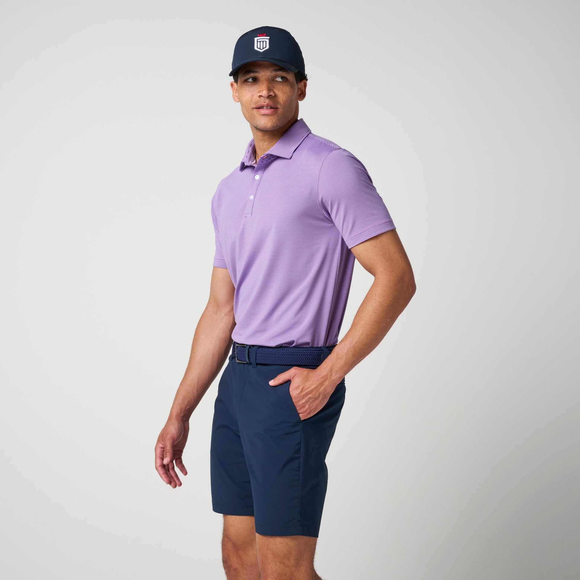 Man wearing lavender short-sleeve polo shirt with horizontal texture and navy shorts.