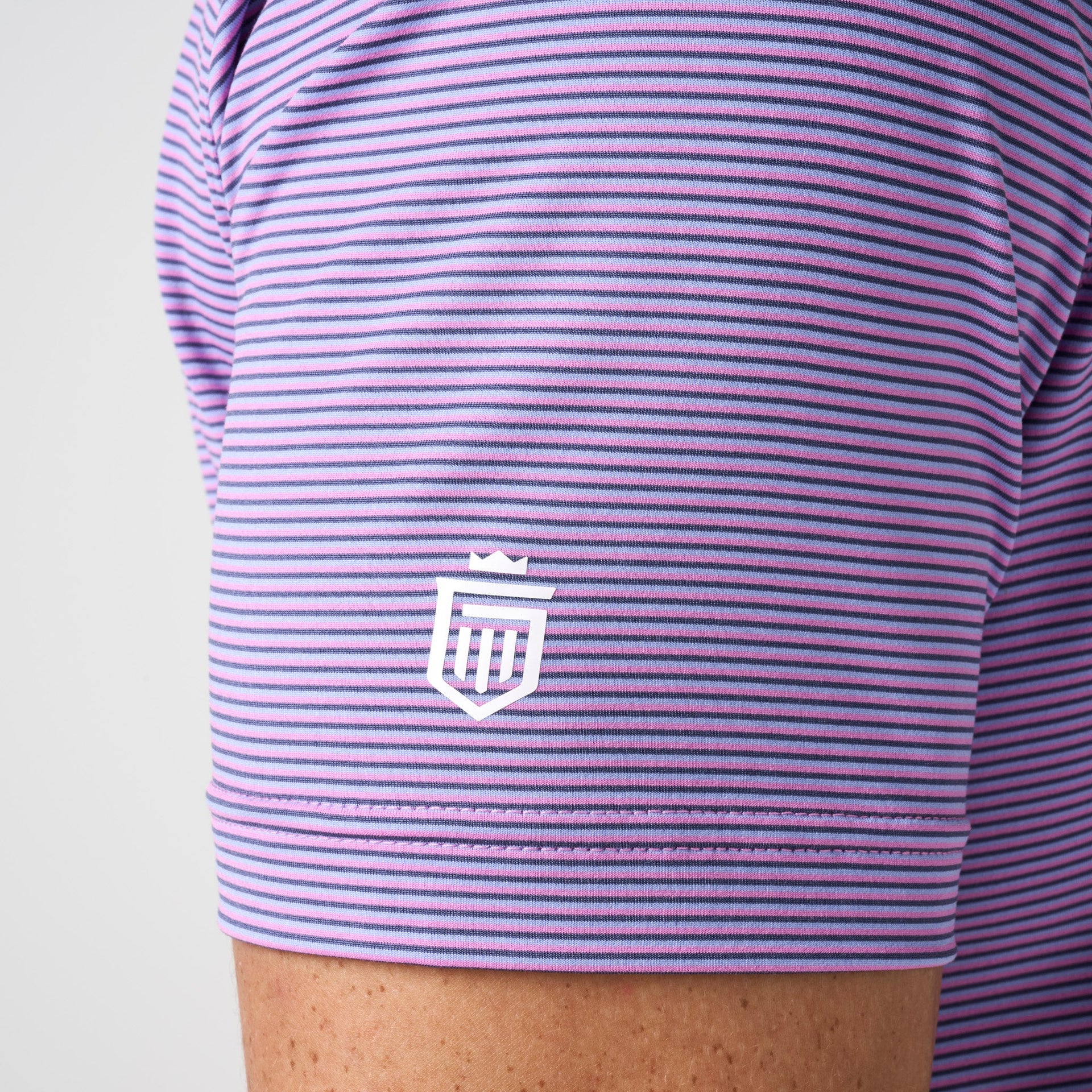 Purple and navy striped polo shirt with white shield logo on chest.
