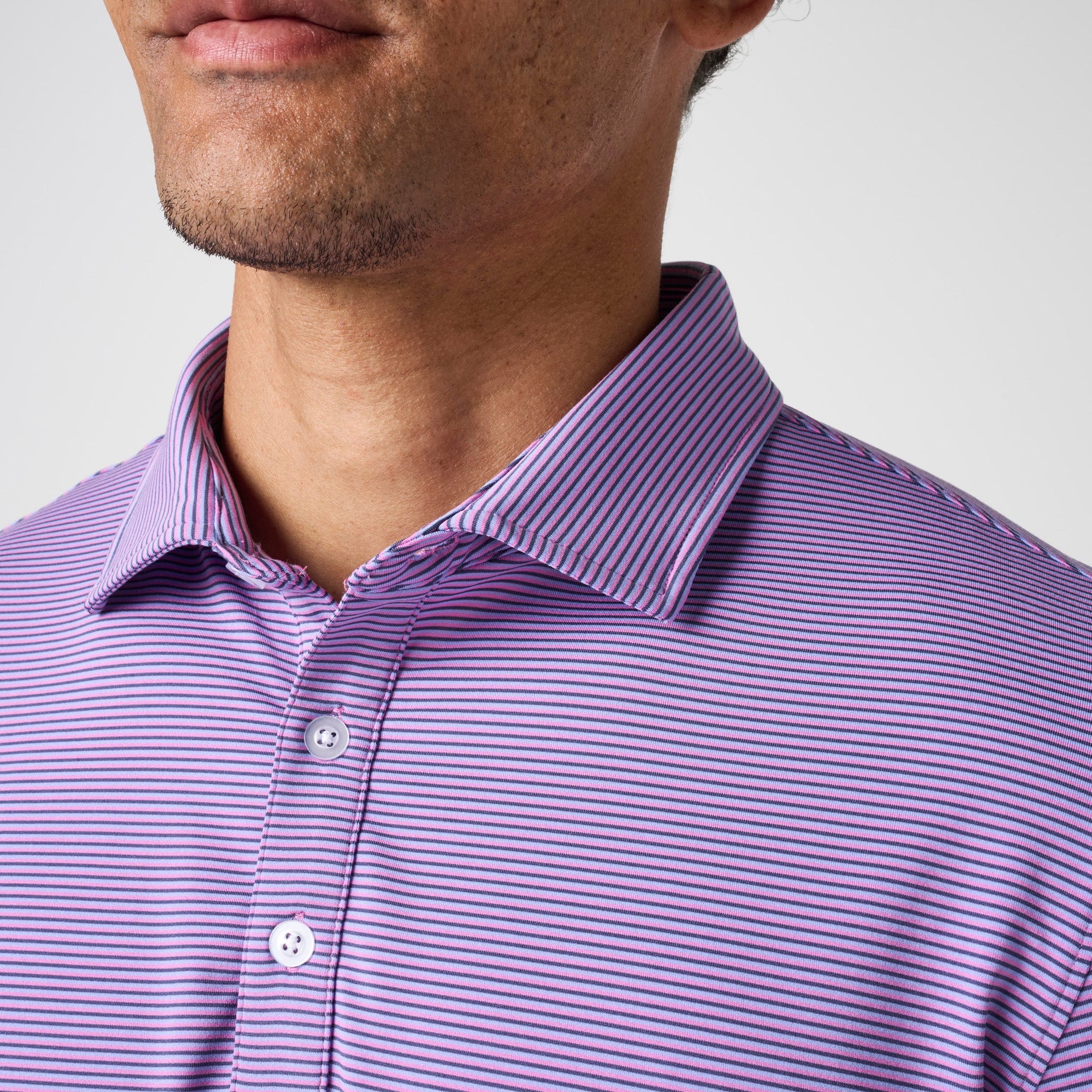 Men's polo shirt with purple and pink horizontal stripes, white buttons, and collared neckline.