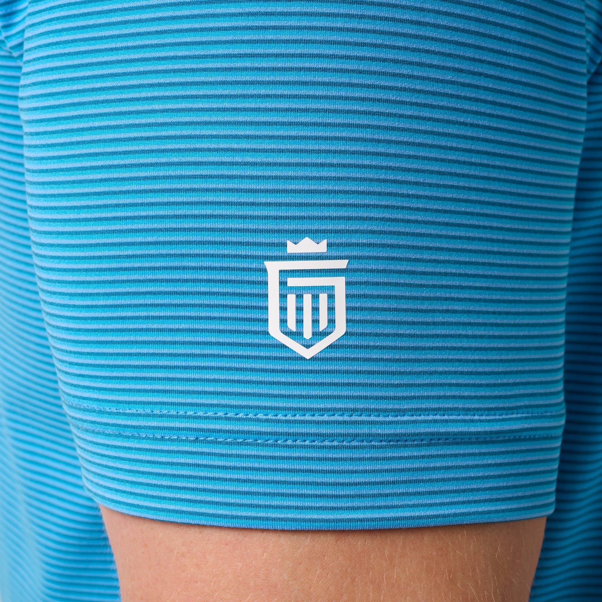 Turquoise striped polo shirt with white shield logo on chest.